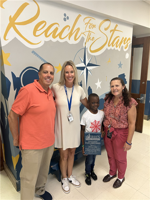 Dercy Iriho, Perry's Stairclimber for November, poses with his plaque and school staff.